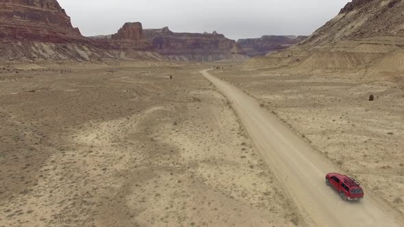 Aerial view following truck driving on dirt road through the Utah desert