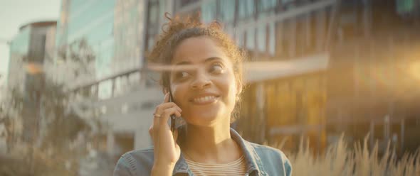 Video of happy Brazilian woman walking with mobile phone outdoors.