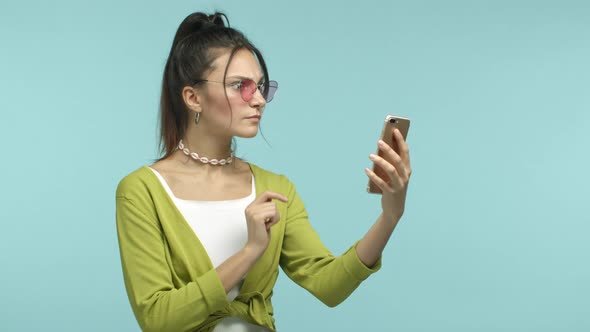 Slow Motion of Stylish Teenage Girl in Sunglasses Tap on Smartphone Shopping Online and Saying Wow