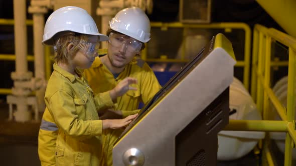 A Young Man and a Little Boy Are Both in a Yellow Work Uniform, Glasses, and Helmet in an Industrial