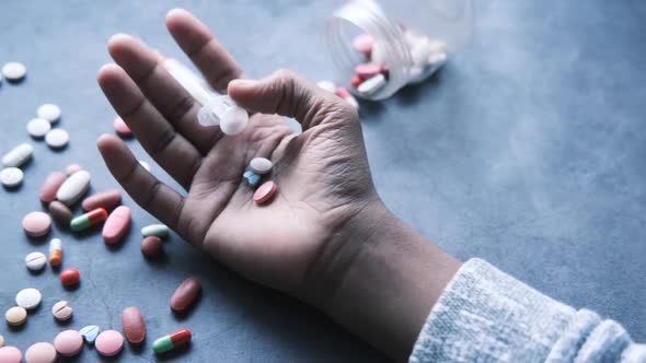 Drug Addiction Concept with Hand Holding Pills and Syringe Laying on Floor