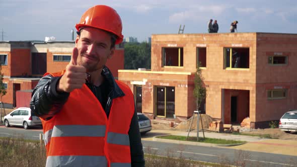 A Young Construction Worker Smiles and Shows a Thumb Up To the Camera