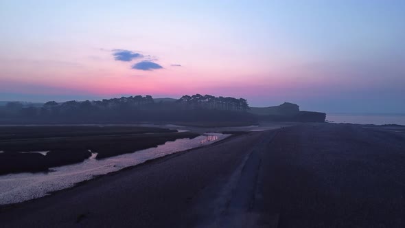 Aerial drone rising pedestal shot of coastal beach seaside at twilight blue hour, England