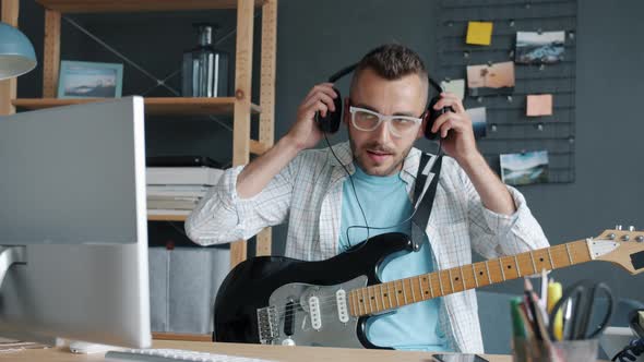 Portrait of Cool Musician Using Computer Then Putting on Headphones and Playing Guitar in Apartment