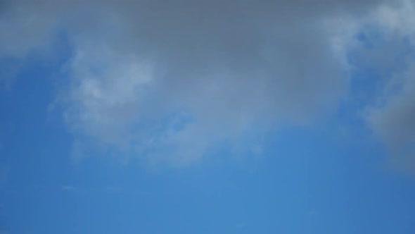 The movement of white clouds against the blue sky. Time lapse