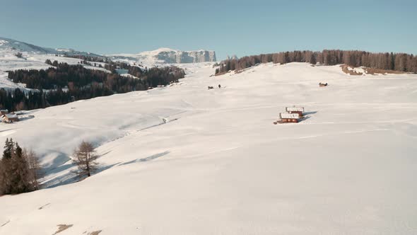 Dolly forward drone shot over thick snow and mountain huts seiser alm italian dolomites