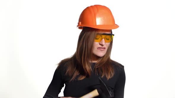 woman in an orange helmet and protective eyeglasses is talking and holding a pen