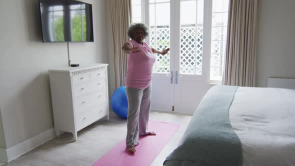 Senior african american woman performing exercise in bedroom at home