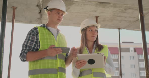 Building in Construction with a Female and a Male Engineers Using a Tablet and Mobile Phone to