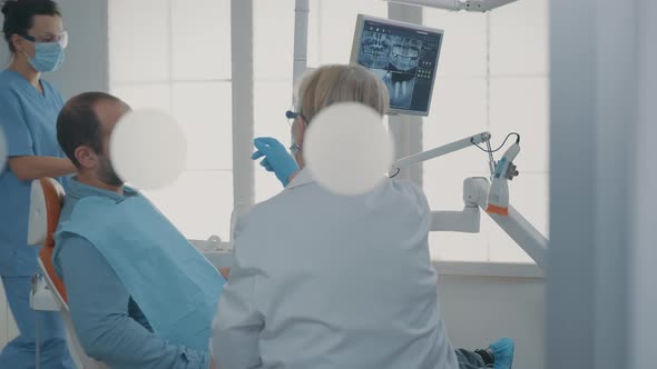 Dentist Pointing at Denture Radiography on Digital Tablet