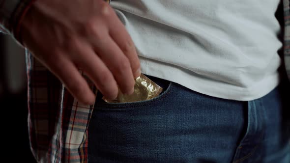 Close Up of Young Man Taking Condom Out of Pocket in Jeans