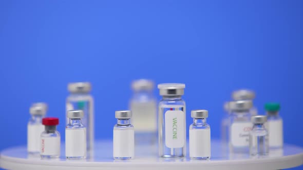 Coronavirus Vaccine in Ampoules Close Up on a Laboratory Table Blue Background