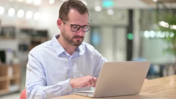 Disappointed Businessman Showing Thumbs Down in Office