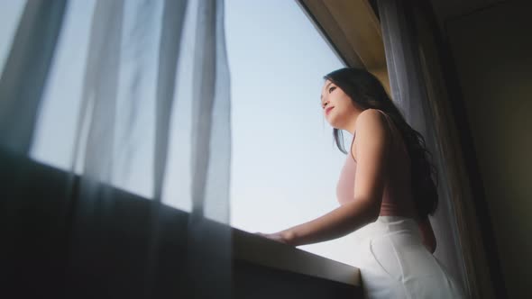 Happy attrative asian woman wearing casual cloth hand pull opening curtains