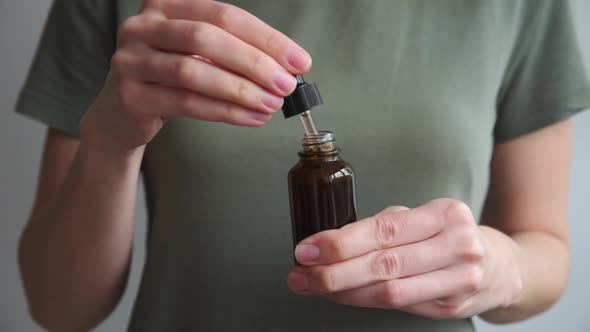 Woman Holds Bottle with Cosmetic Serum and Essential Oil