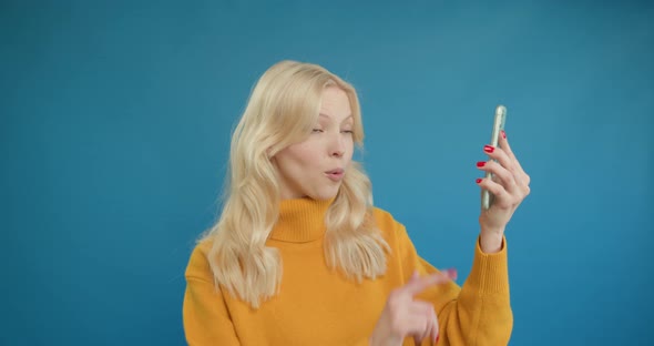 Happy Blonde Woman Looks Surprised Showing Green Screen Phone at Camera