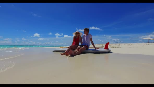 Romantic couple relax on exotic tourist beach adventure by blue green lagoon with white sand backgro