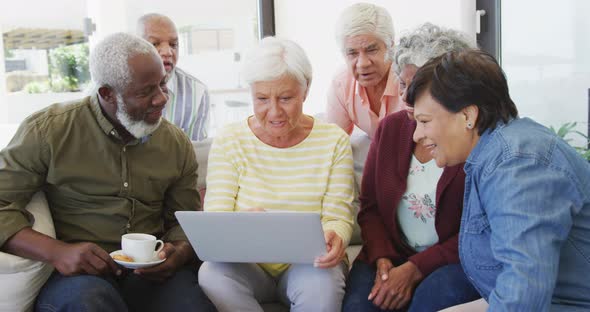 Happy senior diverse people talking and using laptop at retirement home