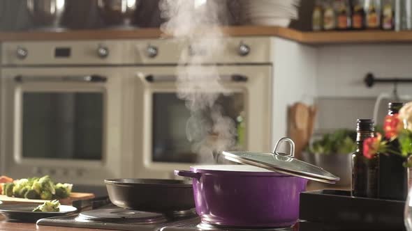 pot of soup or broth is on stove. Steam is coming out of dishes.