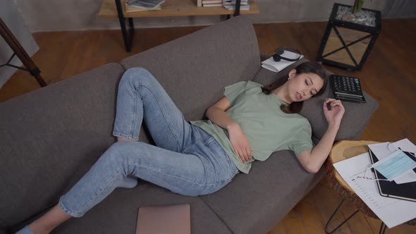 Top View of Exhausted Young Slim Asian Woman Sleeping on Couch in Living Room