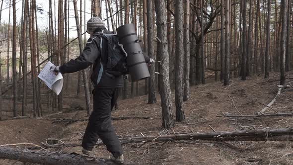 Orienteering in the forest. Tourist on a hike in a forest park with a map.