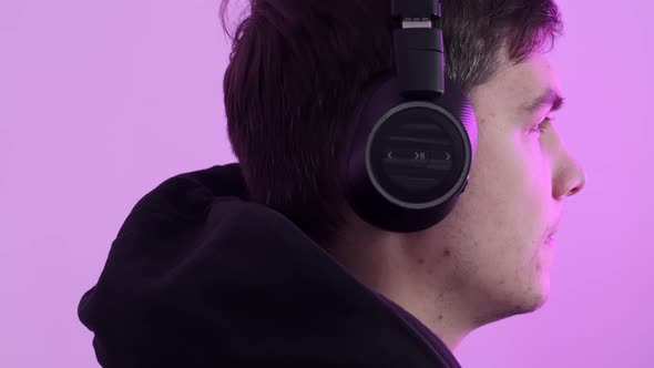 Closeup of a Man Wearing Large Wireless Headphones Playing Computer Games and Getting Emotion From