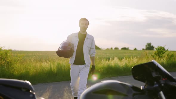 Man Goes to His Motorcicle with Helmet in Hands