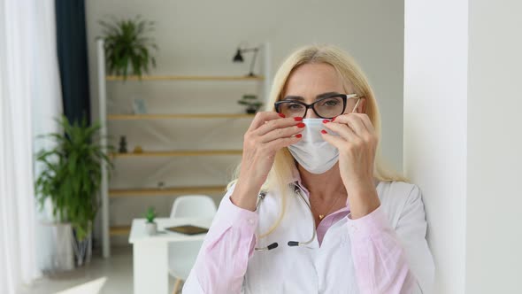 Senior Female Doctor Puts on a Protective Mask