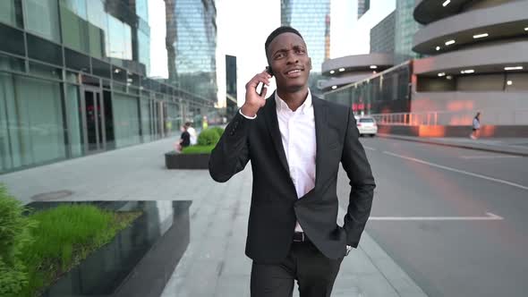 Young black guy walking in the business center and talking on the phone