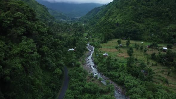 river stream in mountain valley between green forest Amed Bali drone shot