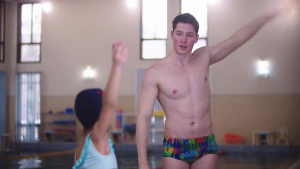 Swimming Instructor Warming Up Their Hands with a Little Girl By the Pool