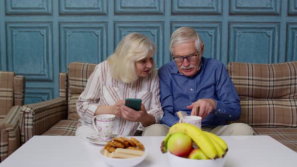 Senior Elderly Couple Grandfather Grandmother Looking on Mobile Phone Making Online Shopping