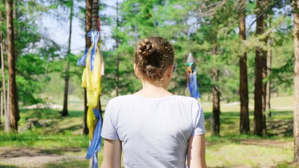 Girl Goes Through the Ritual Gate with Colorful Ribbons in the Forest