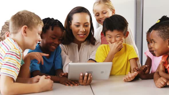 Teacher teaching school kids on digital tablet in classroom