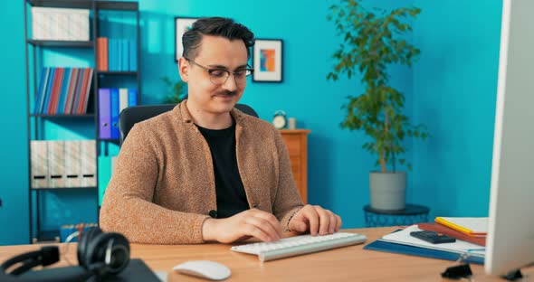 Elegantly Dressed Handsome Man Sitting in Front of the Computer Monitor in the Office and