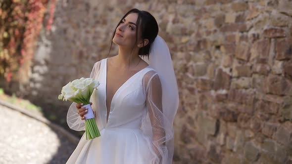 Brunette Bride with a White Bouquet of Flowers in Her Hands