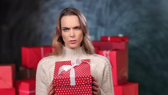 Closeup Portrait Frustrated Blonde Woman Opening Red Gift Box with Bad Present Posing at Gray Studio