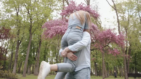 A Young Man Holds His Beloved in His Arms and Whirls with Her Near a Blossoming Tree