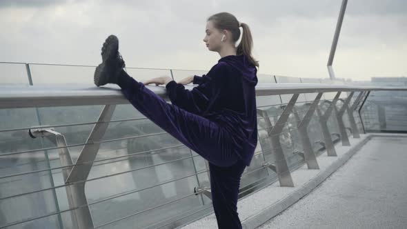 Camera Approaches To Slim Fit Sportswoman Raising Leg and Stretching on Bridge