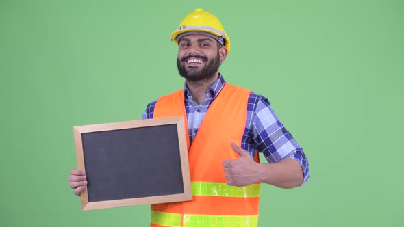 Happy Overweight Bearded Indian Man Construction Worker Holding Blackboard and Giving Thumbs Up