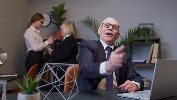 Thoughtful Business Man Using Laptop Sits at Office Desk Workplace Pointing Finger in Eureka Sign