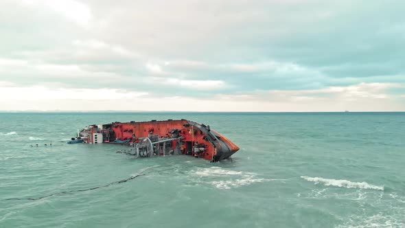 Cargo Ship a Tanker Ran Aground and Rolled Over Into the Sea with Waves in Cloudy Weather, a Man