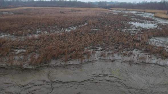 Aerial forward over mud dry river bed field muddy landscape cloudy day