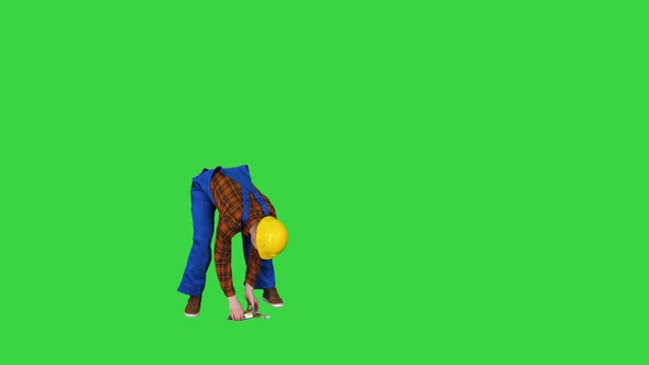 Construction Worker Picking Up Euros From the Floor on a Green Screen, Chroma Key.