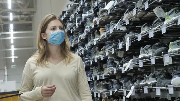 Young Woman Going Through Children's Shoes Section of Empty Store