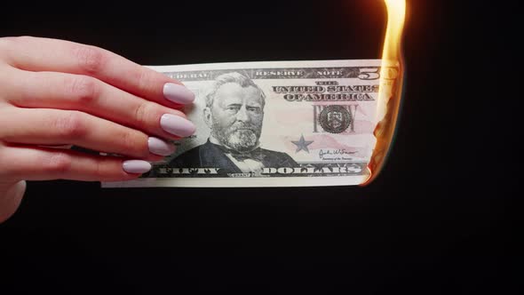 Woman Holding Burning American Fifty Dollar Banknote on Black Background