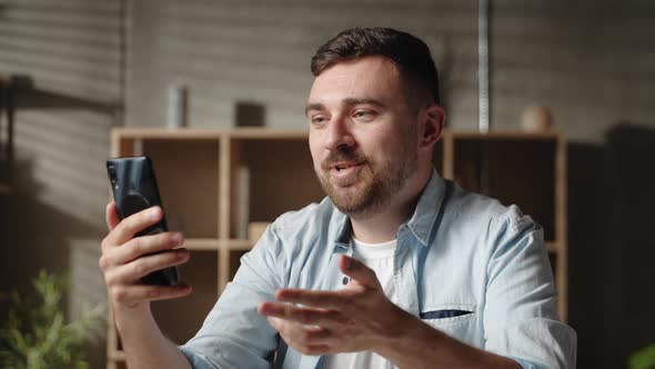 Happy Young Handsome Caucasian Man Looking at Smartphone Screen Holding Web Camera Video