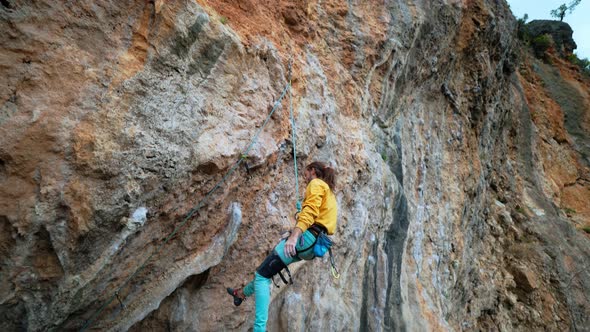 Slow Motion of Joyful Handsome Man Rock Climber in Yellow Sweatshirt with Long Hair Hanging on Rope