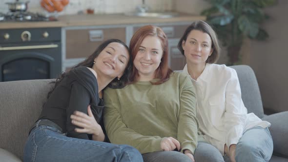 Friendly Young Women Sitting on Couch Looking at Camera and Smiling