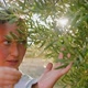 Cute Young Mom Hold Little Child in Her Arms and Showing Olive Tree in the Garden - VideoHive Item for Sale